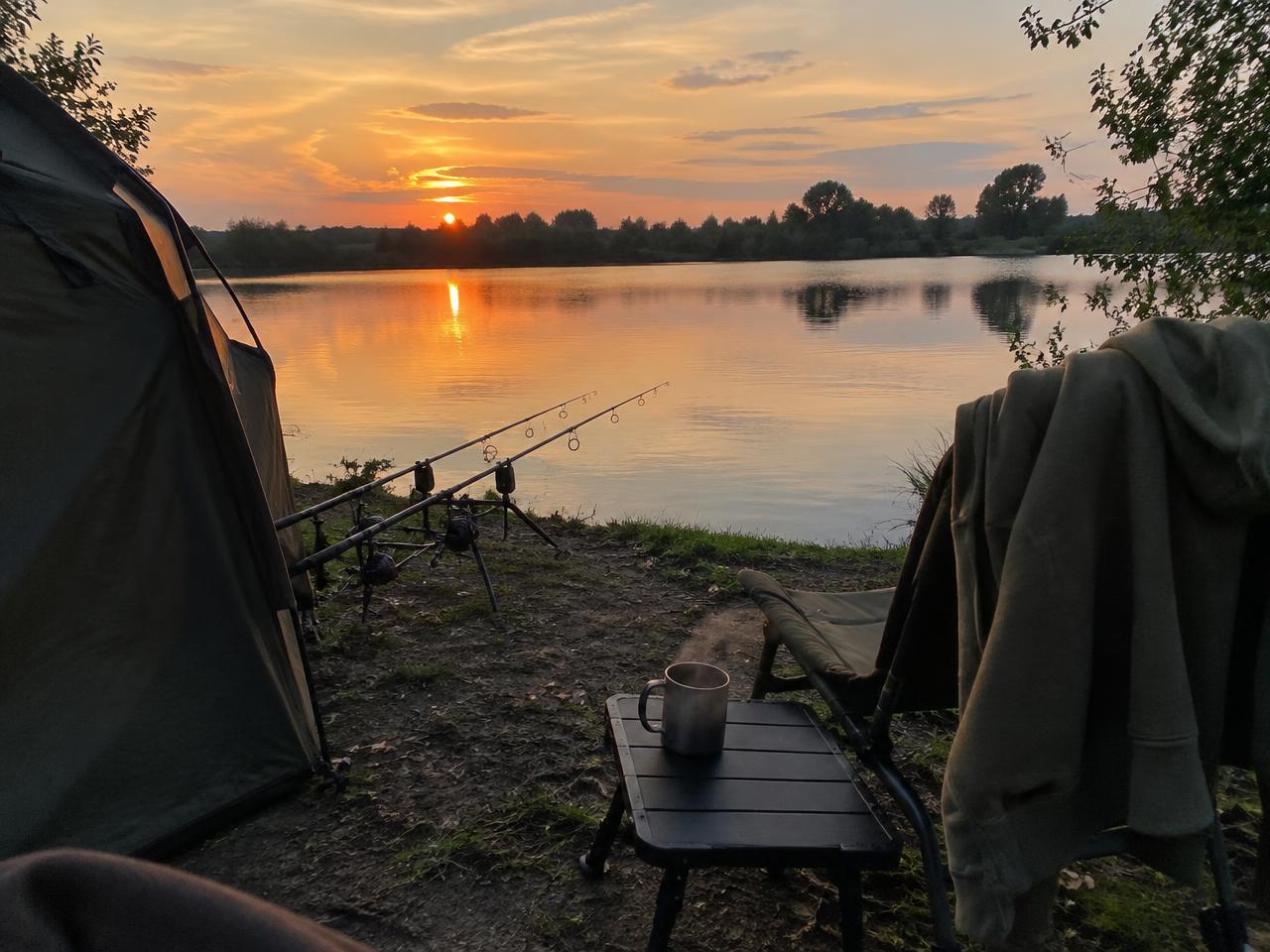 An angler in an olive hoodie fishing at dusk